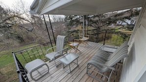 Eine Holzterrasse mit Metallgeländern, zwei Stühle, ein kleiner Tisch und eine Couch.