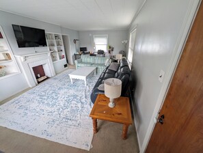 Een woonkamer met een open haard, een televisie, een bank en een salontafel.