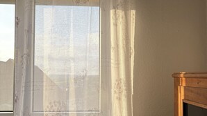 A room with a window covered by a sheer curtain with floral and butterfly patterns.