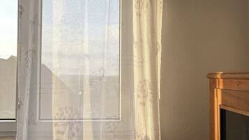 Ein Zimmer mit einem Fenster, das mit einem transparenten Vorhang mit floralem und Schmetterlingsmuster verziert ist.