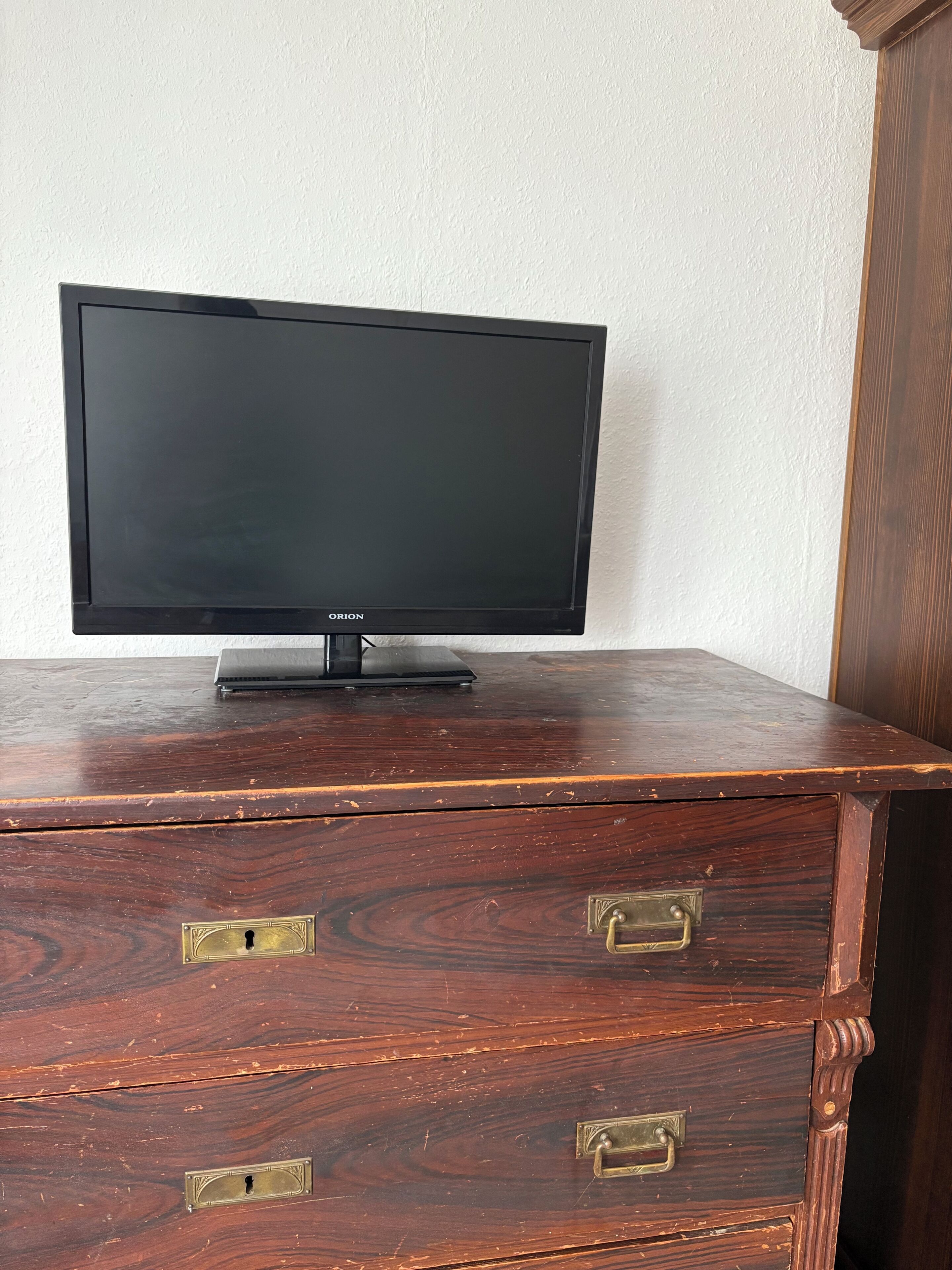 A television on a wooden dresser with two drawers and a cabinet.