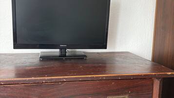 A television on a wooden dresser with two drawers and a cabinet.