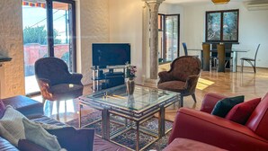 A spacious living room with a red sofa, a glass coffee table, and a television. There is a large window providing natural light and a view of the outdoors. - Gorgeous apartment in Opric with house sea view (Opric)