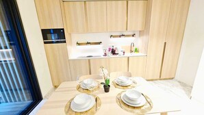 A modern kitchen with wooden cabinets, a built-in microwave, and a countertop with various appliances and decorations. - Cosy Terrace Studio close to city center (Luxembourg City)
