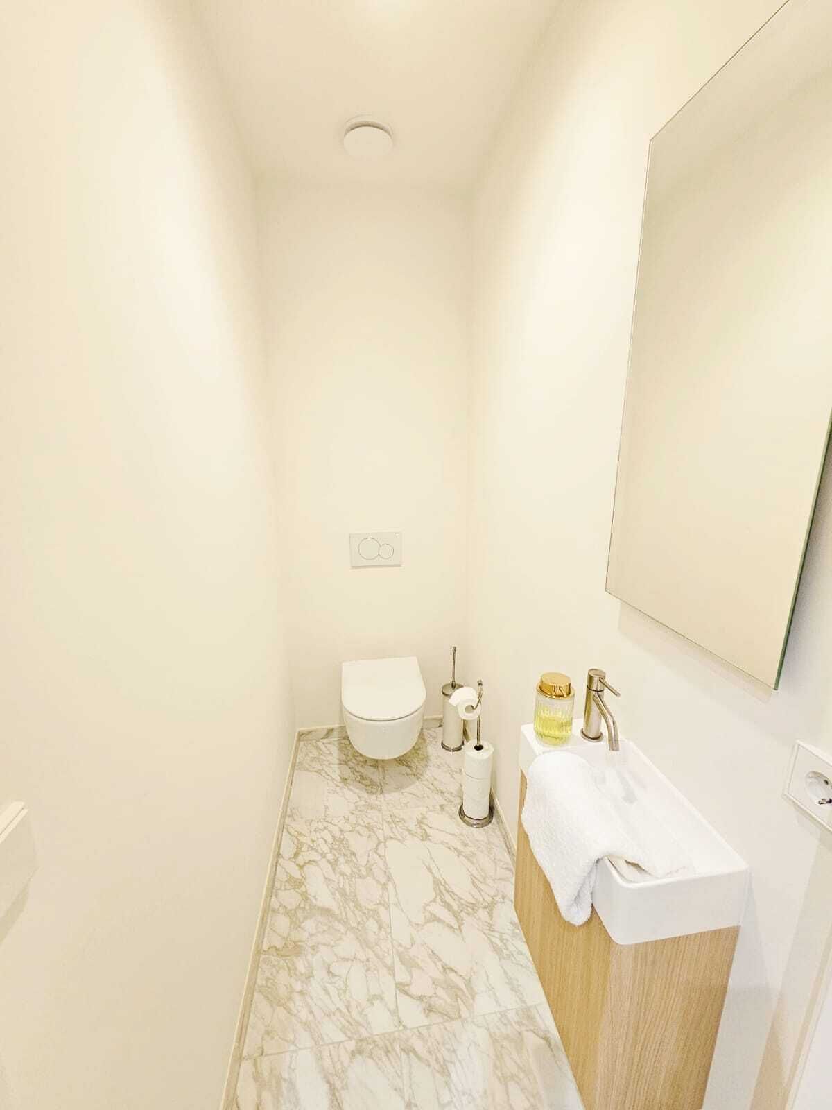 A compact bathroom with a toilet, sink, and mirror.