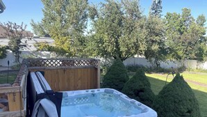 A hot tub in a backyard with a wooden fence, neatly trimmed bushes, and a brick pathway. - Guest Favorite, 5 Star Cozy 1-bedroom corporate apartment in perfect West Jordan (West Jordan)