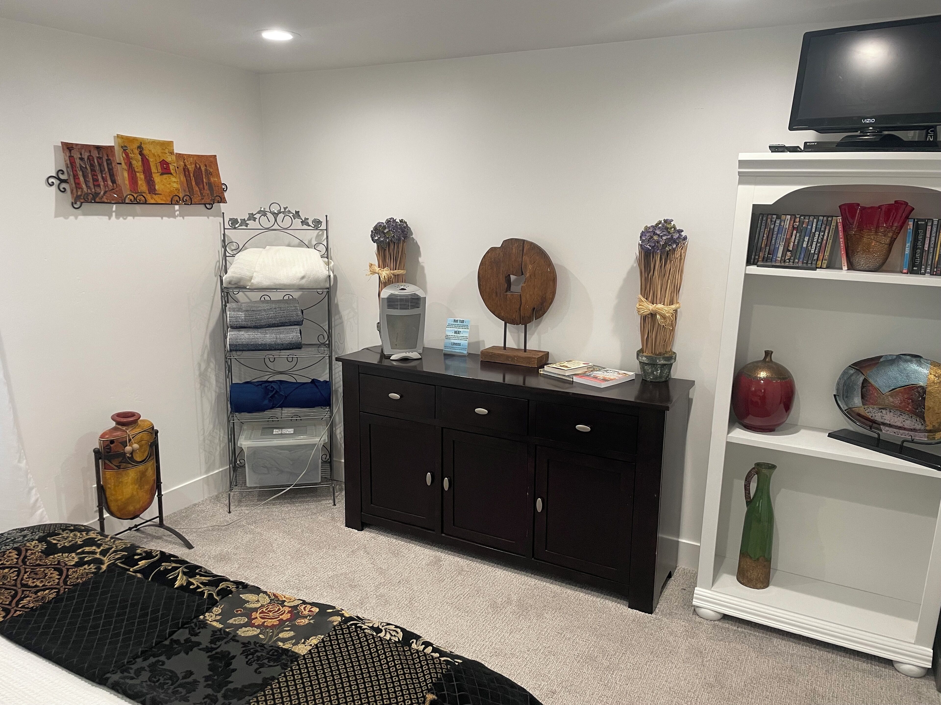 Um quarto bem organizado com cama, penteadeira, televisão e estante.