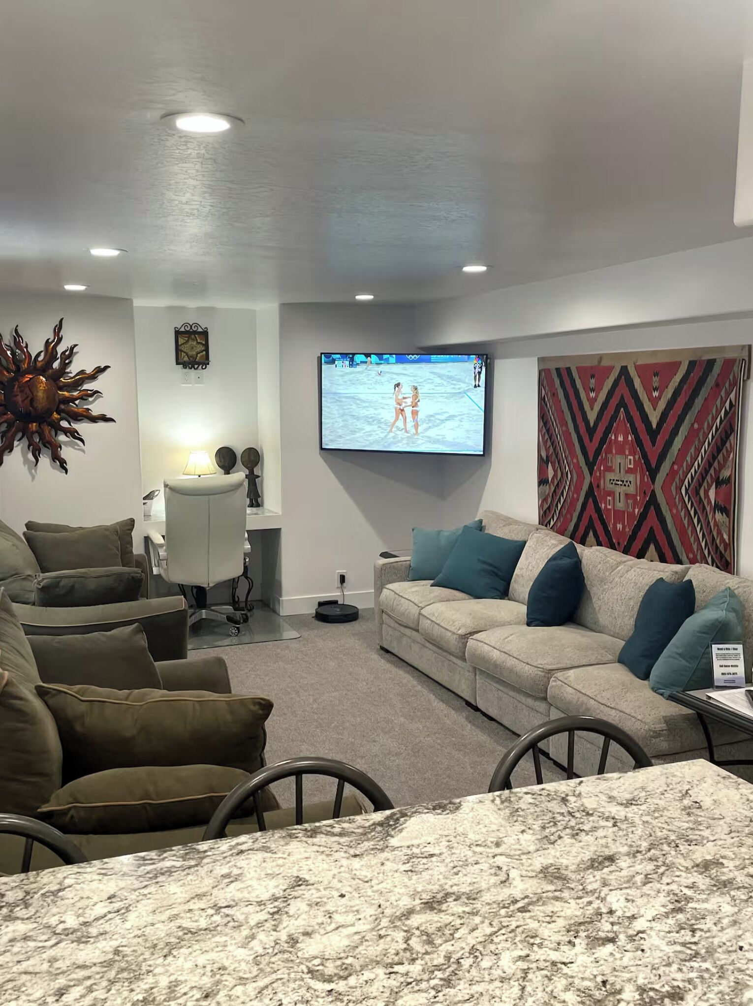 Un salon moderne doté d’un grand téléviseur à écran plat, d’un canapé, d’une table basse et d’un élément décoratif mural.