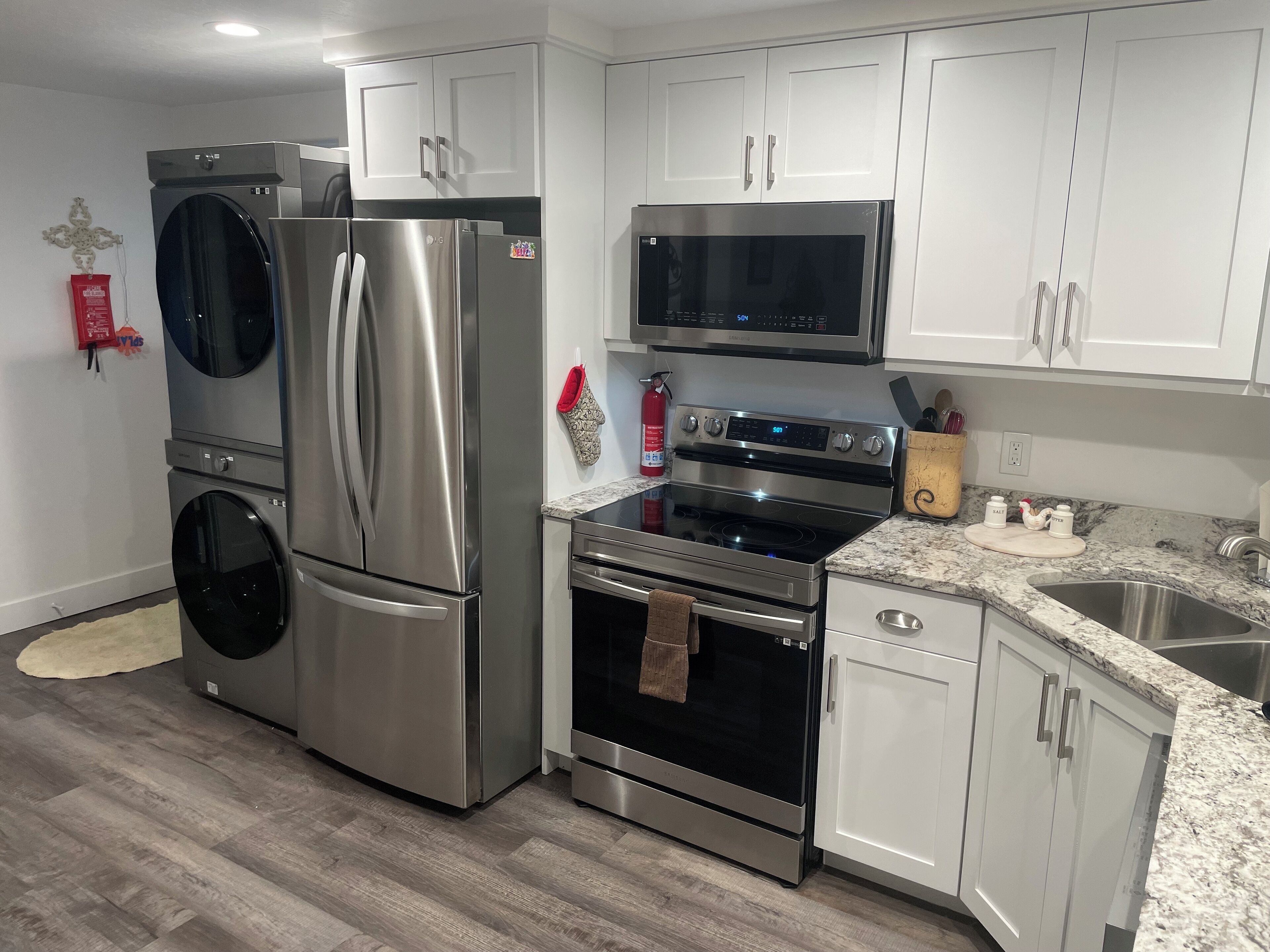 A modern kitchen with stainless steel appliances, white cabinetry, and a granite countertop.