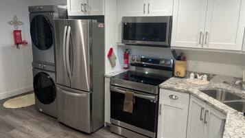 A modern kitchen with stainless steel appliances, white cabinetry, and a granite countertop.