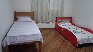 A room with a wooden bed and a red single bed, both with white bedding. - A house to enjoy and take advantage of beaches, waterfalls, and many adventures in Ilhabela. (Ilhabela)