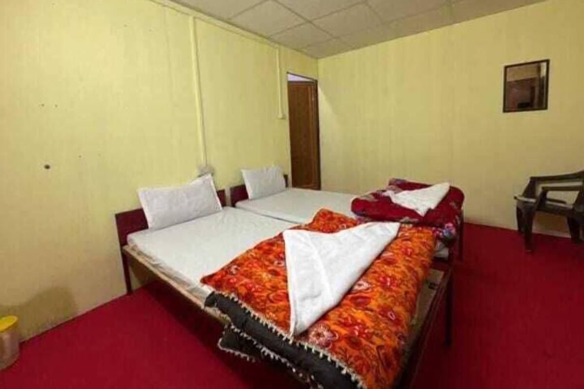 A room with two beds, a wooden desk, and a door.
