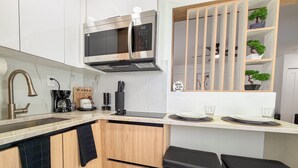 A modern kitchen with a built-in microwave, stainless steel sink, and wooden cabinets. - Modern Luxury Studio • Kitchen, Wi-Fi & Private Parking (Pembroke Pines)