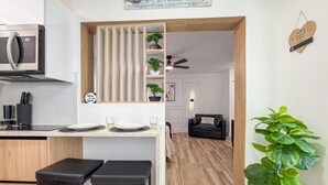 A modern kitchen with a microwave, two bar stools, a wooden cabinet, and a sign that says "FAMILY". - Modern Luxury Studio • Kitchen, Wi-Fi & Private Parking (Pembroke Pines)