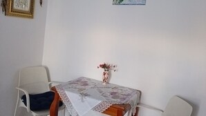Een eetgedeelte met een tafel bedekt met een kantkleed, twee witte stoelen en een vaas met bloemen.