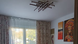 Een slaapkamer met een bed, bloemen gordijnen, een plafondventilator en kunst aan de muur.