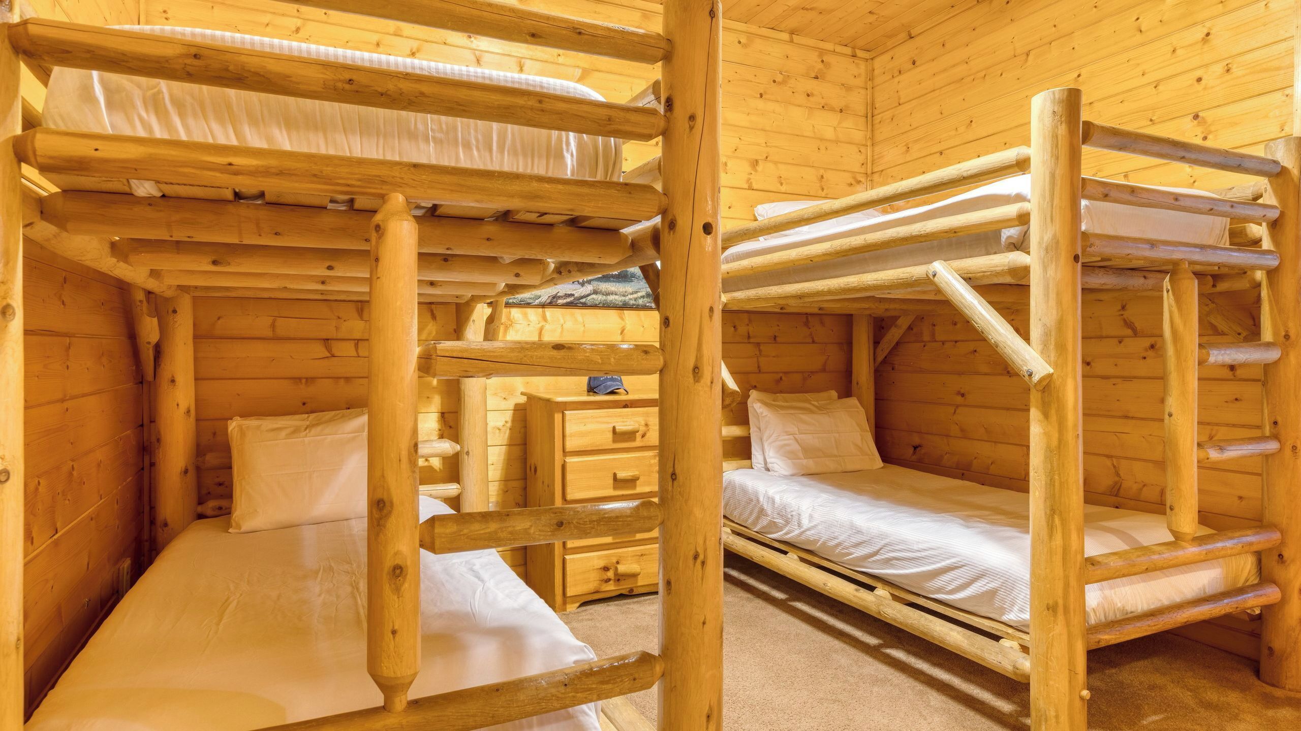 A wooden cabin with bunk beds, a small dresser, and a window.