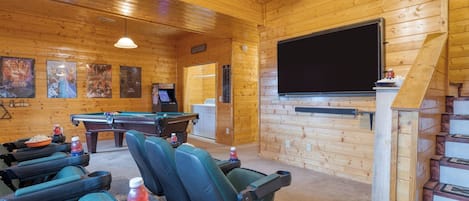 Ein gemütliches Zimmer mit Billardtisch, bequemen Sitzgelegenheiten, einem Fernseher und einer Waschgelegenheit.