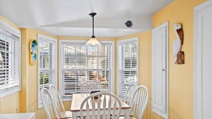 A dining area with a table and chairs, large windows with blinds, and a ceiling fan. - BeachTimes and TanLines|GolfCart|Linens|OceanLakes (Horry County)