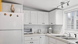 A kitchen with white cabinets, a built-in oven, a microwave, a toaster, and a sink. - BeachTimes and TanLines|GolfCart|Linens|OceanLakes (Horry County)