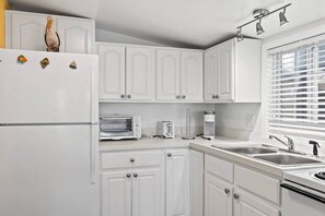 A kitchen with white cabinets, a built-in oven, a microwave, a toaster, and a sink. - BeachTimes and TanLines|GolfCart|Linens|OceanLakes (Horry County)