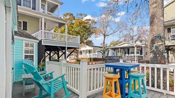 A wooden deck with rocking chairs and a table, surrounded by white railings. - BeachTimes and TanLines|GolfCart|Linens|OceanLakes (Horry County)