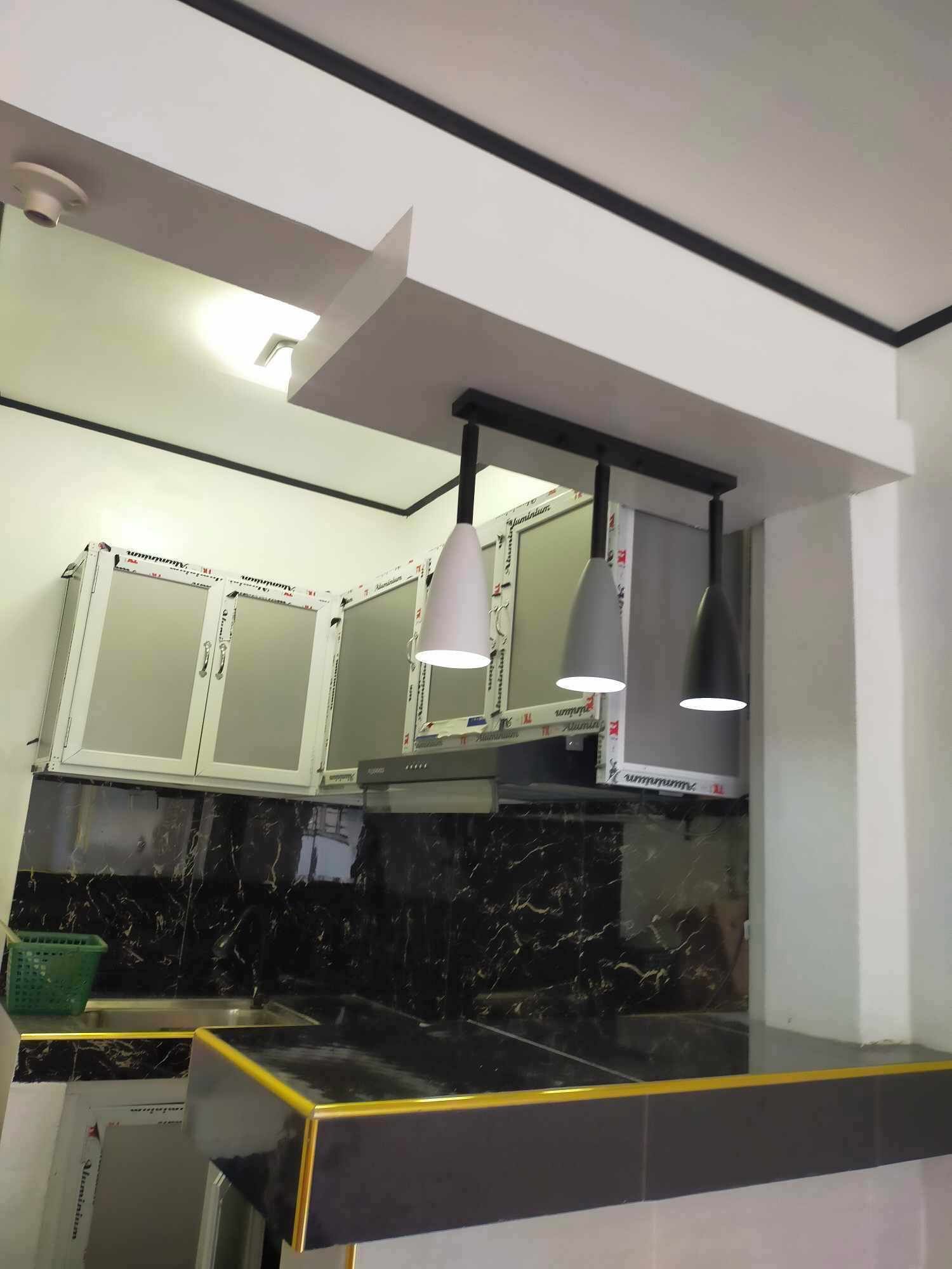A kitchen with white cabinets, black marble backsplash, and a black countertop.