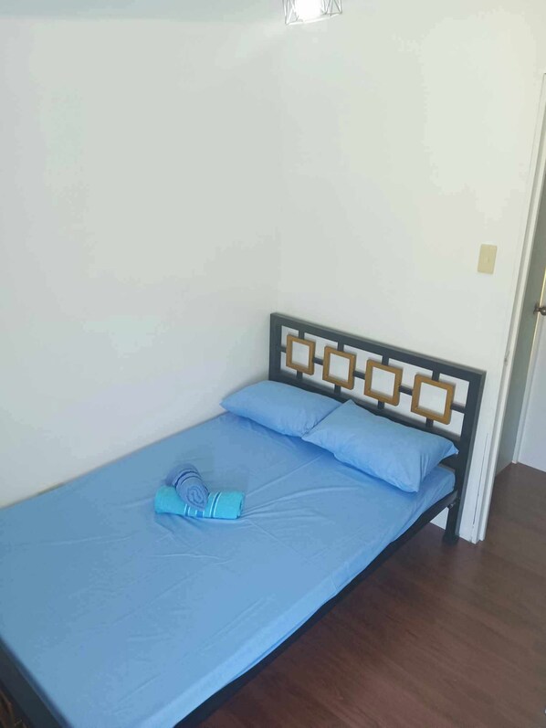 A single bed with a wooden headboard and a blue mattress.