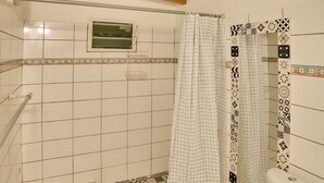 Un bagno con il water, doccia con tenda decorata e pavimento piastrellato.