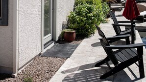 Een gebouw met een witte gevel, een schuifdeur en een kleine tuin met een bloempot.