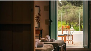 A room with a bed, a chair, and a table near a window with a view of greenery. - Traditional Anna's Stone House with Private Pool (Margarites)
