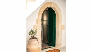 A large terracotta pot with a plant, an arched doorway with a green door, and a doormat on the floor. - Traditional Anna's Stone House with Private Pool (Margarites)