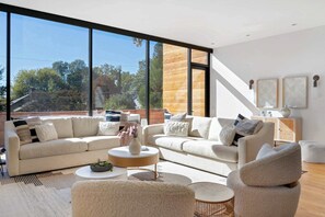 A modern living room with a large window, a sofa set, a coffee table, and a side table with a vase. - Axiom Haus (Atlanta)