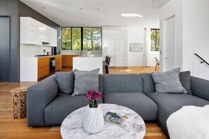 A modern living room with a grey sectional sofa, a marble coffee table, and a vase with flowers. - Axiom Haus (Atlanta)