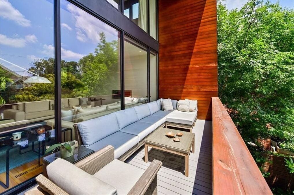 Un espace extérieur moderne, aménagé avec une structure en verre, une terrasse en bois et une végétation luxuriante.