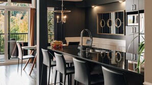 A modern kitchen with a central island, black countertops, and stainless steel appliances. - Prestige Ski in Ski out Sommet Saint-Sauveur 3BR (Saint-Sauveur)