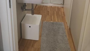 A modern bathroom with a white sink, glass shower enclosure, and a small white storage box. - Short Rent Milan Porta Romana  (Milan)