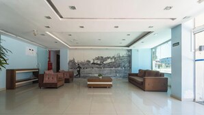 Un vestíbulo moderno con un mural grande, dos sofás, una mesa de centro y un mostrador de recepción.