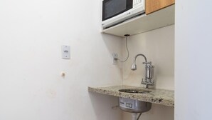 Eine kleine Küche mit Mikrowelle, Spüle und Arbeitsplatte.