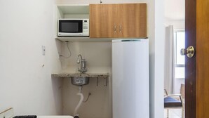 Eine kleine Küche mit einer Mikrowelle, einem Spülbecken mit Armatur und einem Kühlschrank.