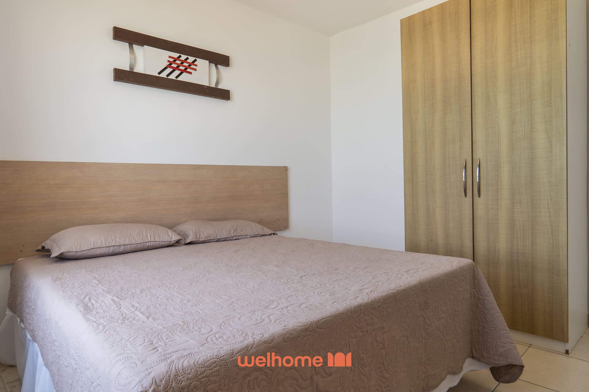 Un dormitorio con cama, cabecero de madera, armario y una obra de arte en la pared.
