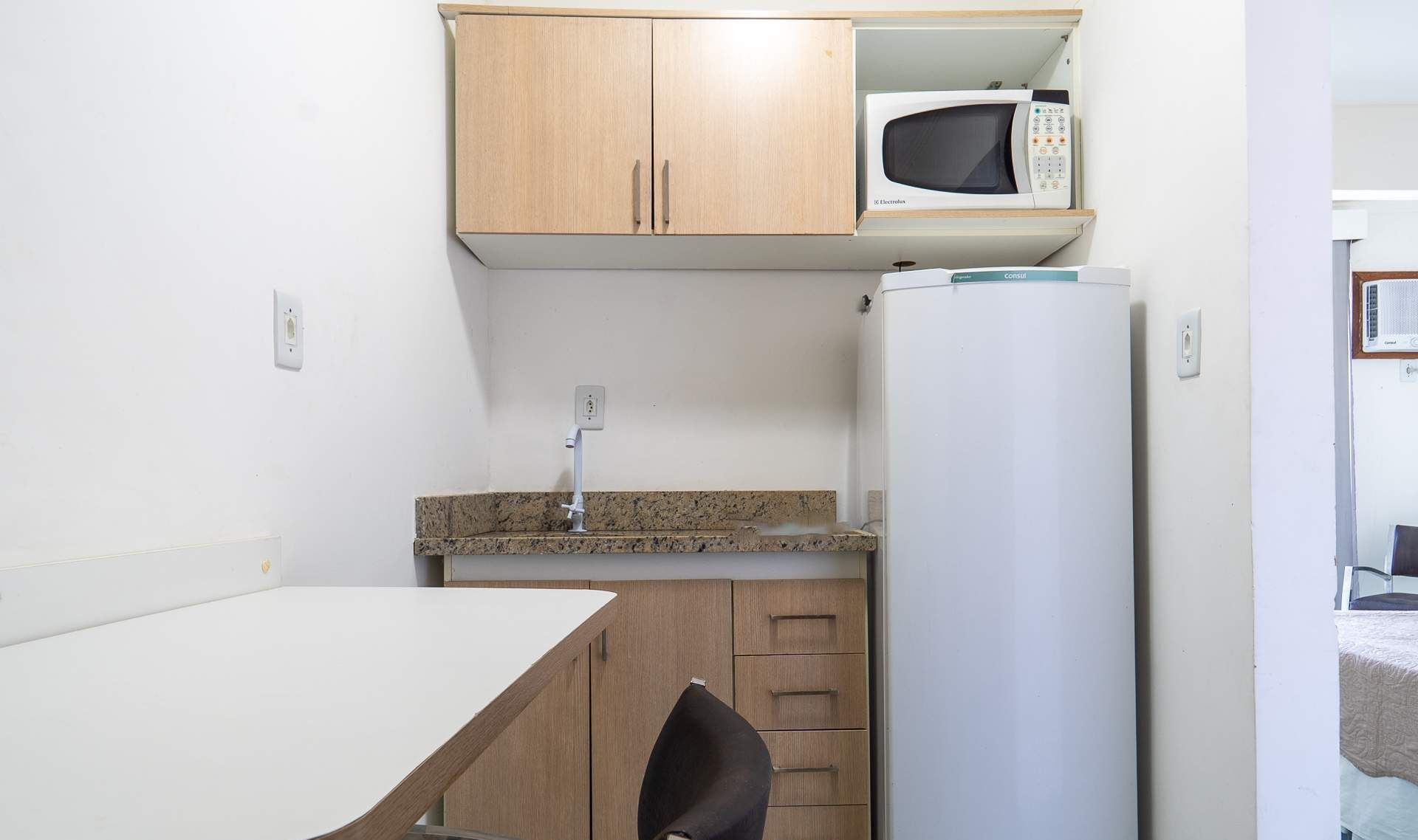 A compact kitchenette with a microwave, a refrigerator, a sink, and a small dining table.