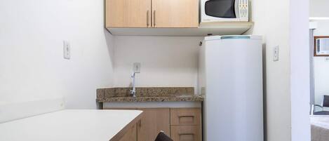 A compact kitchenette with a microwave, a refrigerator, a sink, and a small dining table.