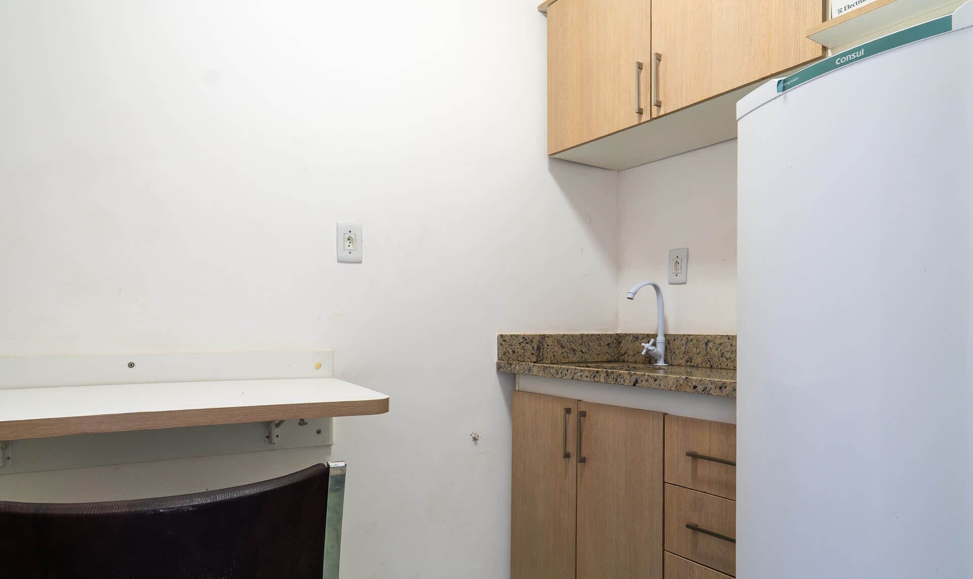 Una pequeña cocina americana con mostrador, pileta y muebles de madera.