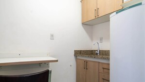 A small kitchenette with a countertop, sink, and wooden cabinets. - Apartamento no Centro de Macae Proximo a Praia (Macaé)