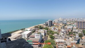 Eine Küstenstadt mit einer Mischung aus Wohn- und Geschäftsgebäuden, einem Strand und freiem Blick auf den Ozean.