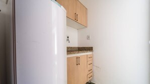 Eine Küche mit einem weißen Kühlschrank, Holzschränken, einer Arbeitsplatte aus Granit und einem grün gefliesten Boden.