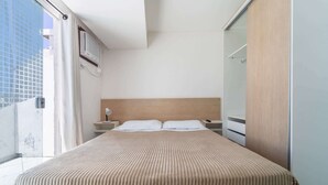Ein Hotelzimmer mit einem Bett, einem Nachttisch, einer Lampe und einem Kleiderschrank.
