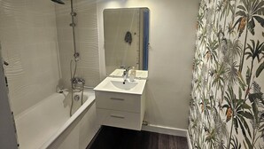 Une salle de bain avec une baignoire, un lavabo et un miroir.