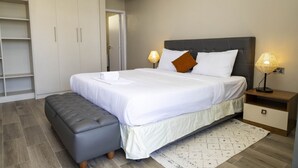 Una camera da letto con un letto, lampade sui comodini, una panca e un armadio.